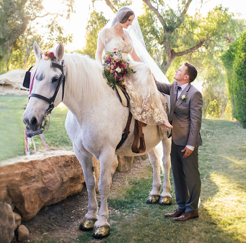 Bride in Claire Pettibone on white horse at wedding