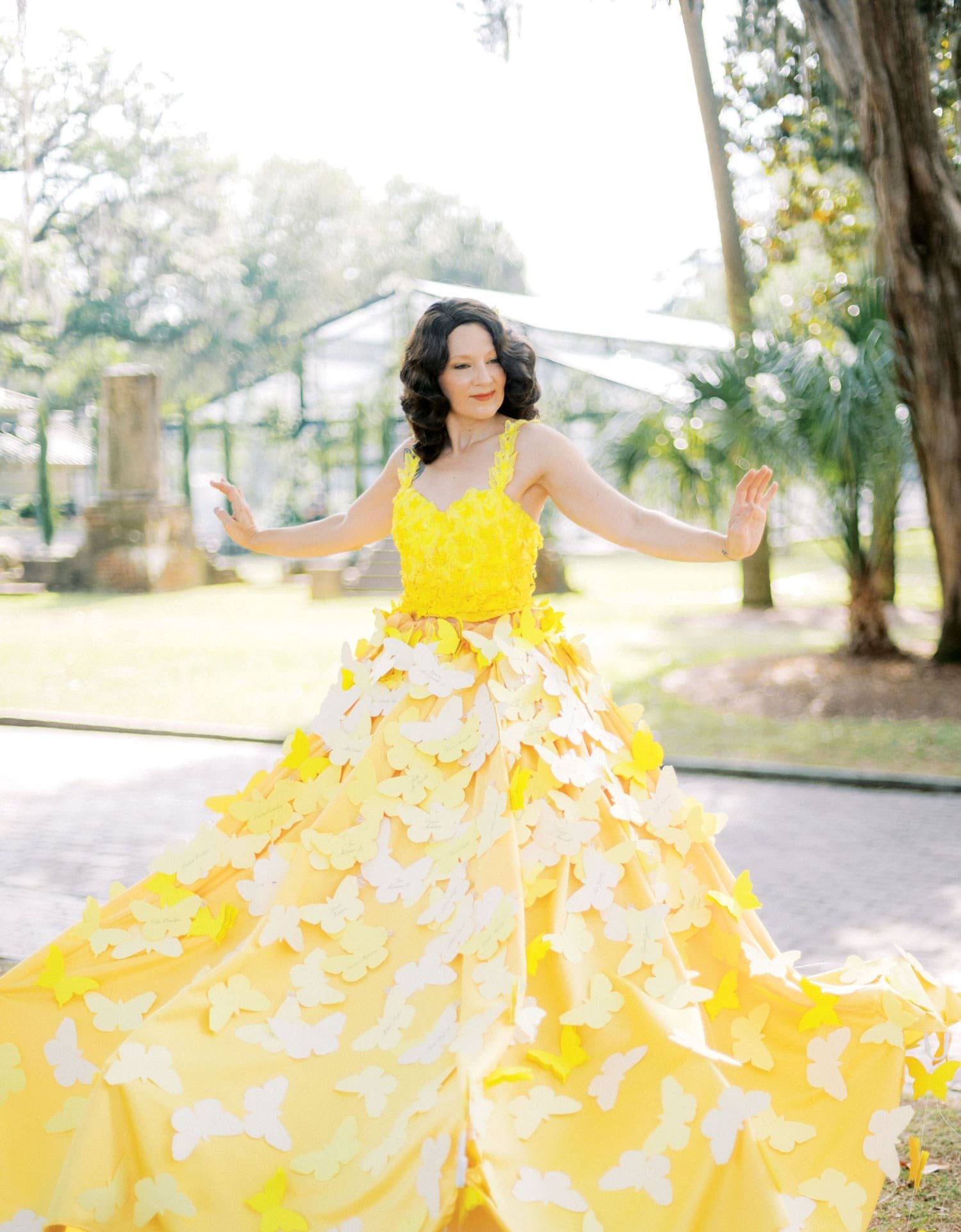 entertainer wearing yellow dress with butterfly escort cards attached at wedding