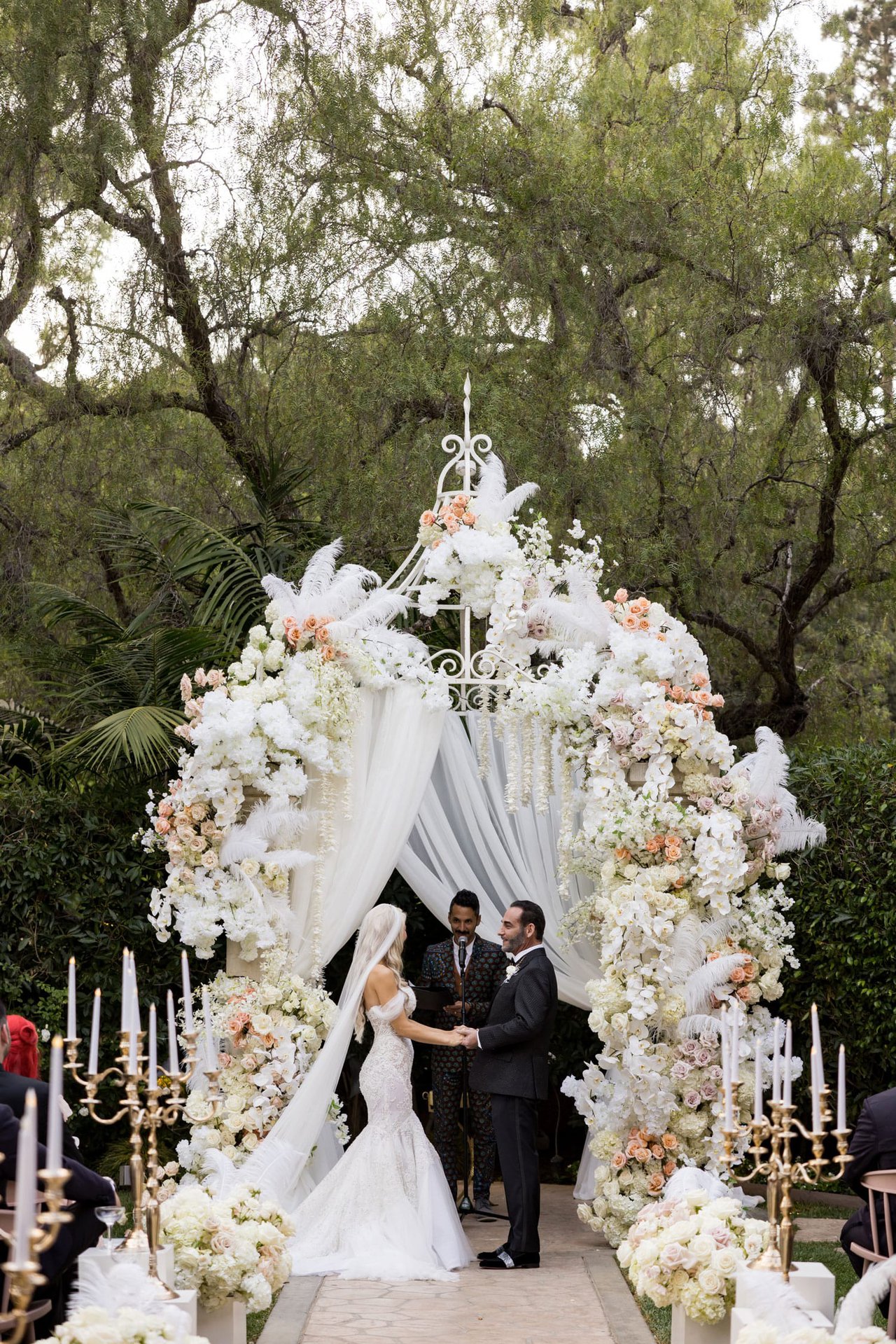 Vow Exchange Under Floral & Feather Ceremony Arch
