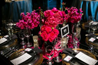 Low Floral Arrangement on Dark Tablescape low-centerpiece-with-bright-pink-hot-pink-flowers-on-black-table-decorations-gold-plates