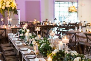 Rustic Elements at Whiskey Distillery candlelight-and-tall-centerpieces-with-long-wooden-tables-and-greenery