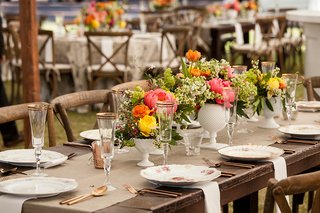 Colorful Small Centerpieces in White Vessels white-vases-on-rustic-wedding-wood-table-with-pink-peony-orange-yellow-flowers-greenery-rose-gold
